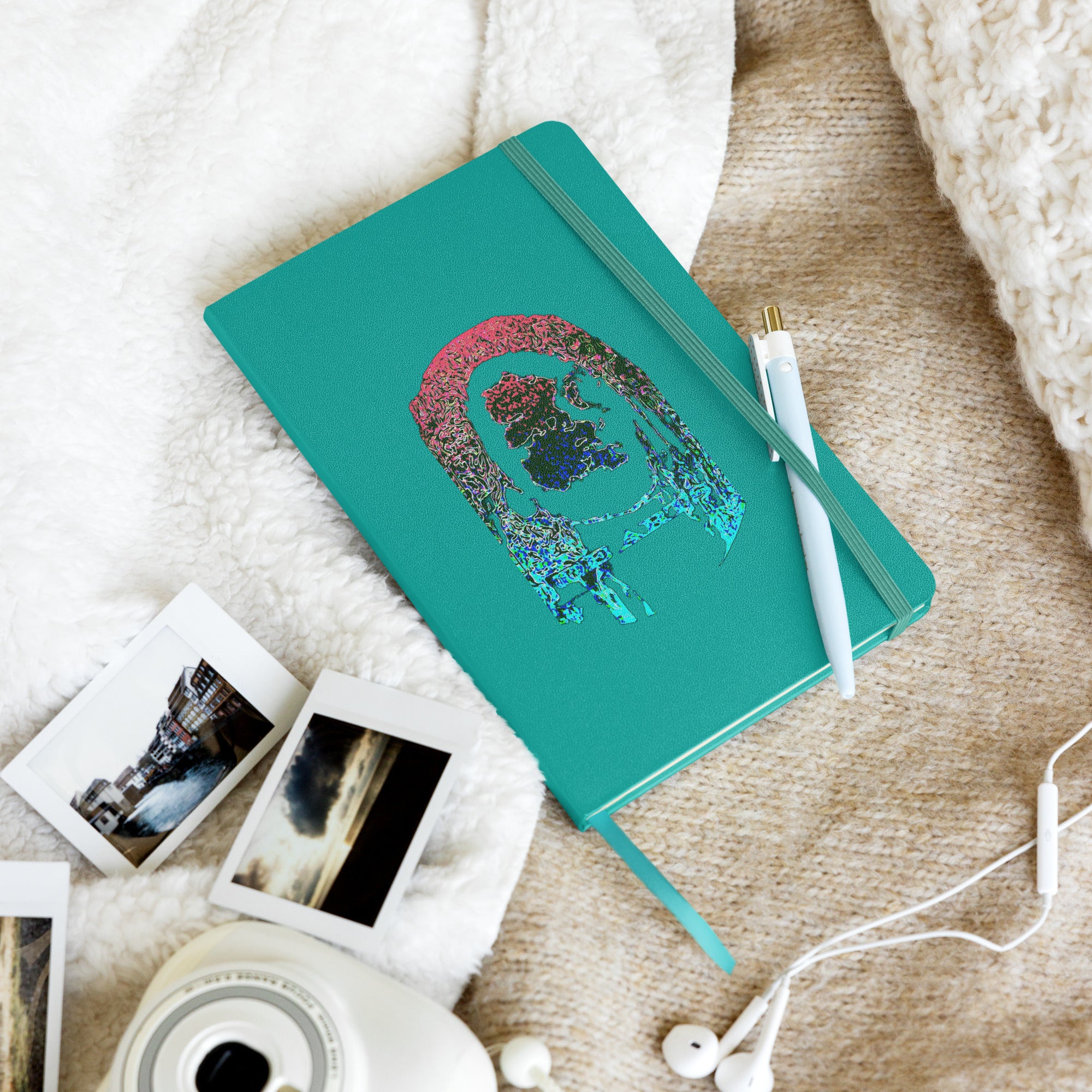Teal notebook with a colorful design on a textured surface with photos and a camera.